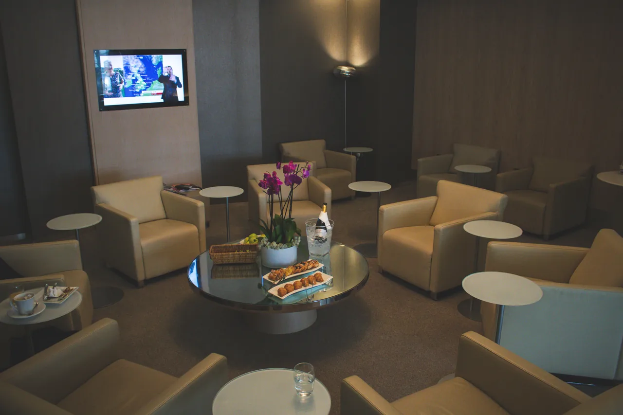 Elegant airport lounge with beige leather seats and orchid decor, offering comfort and luxury food service
