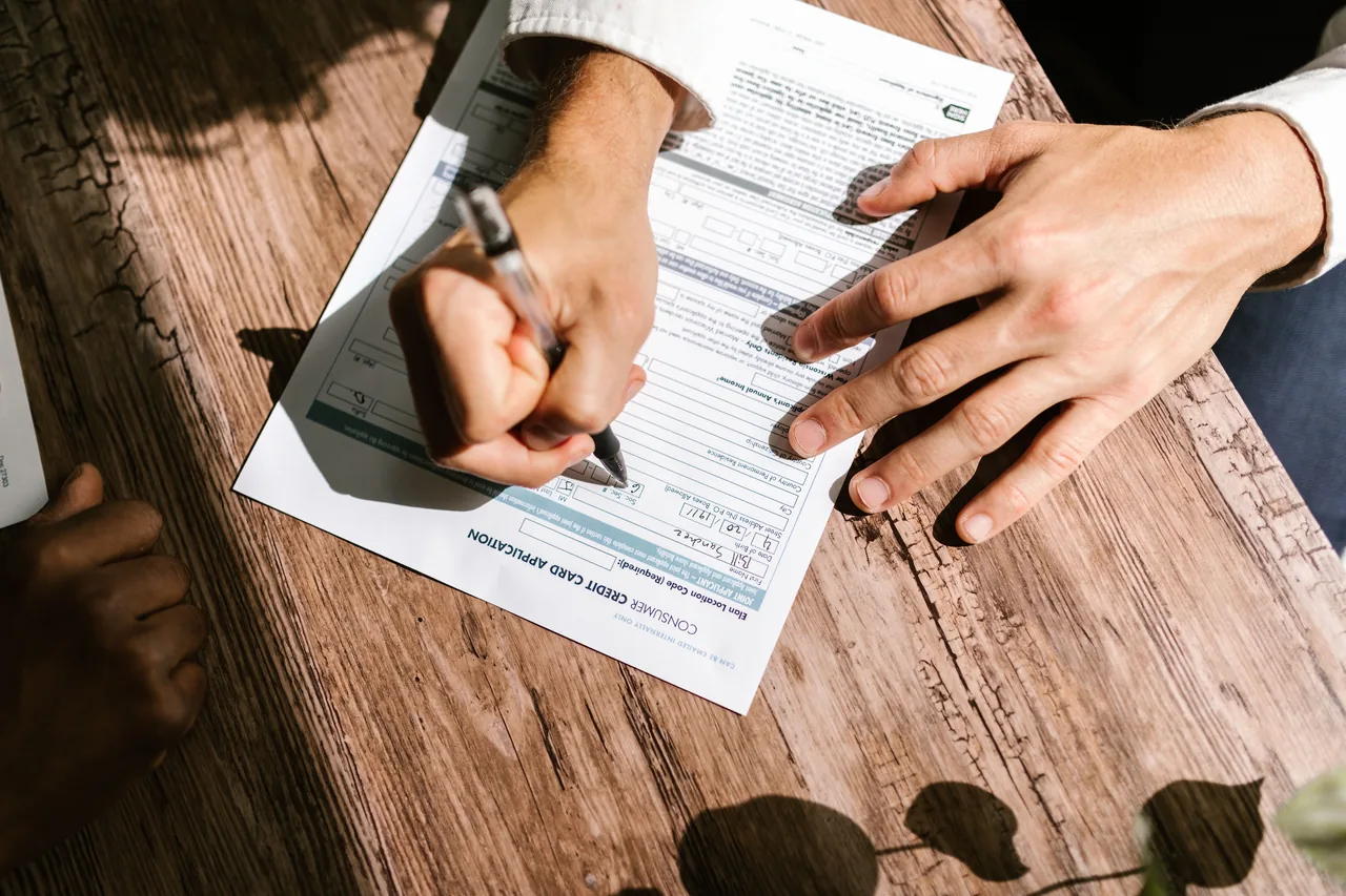 Hands writing on a consumer loan credit application form on a wooden table
