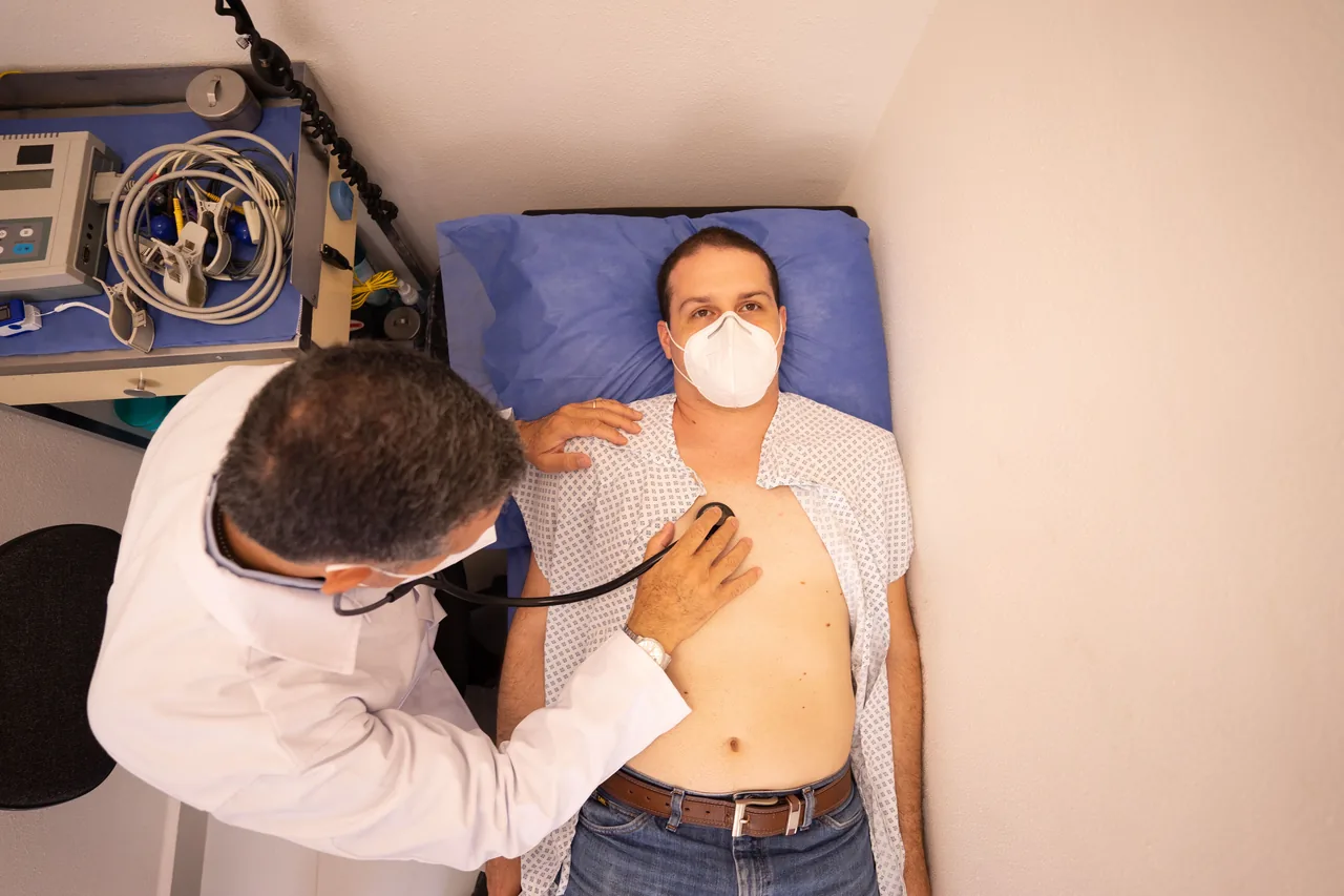 Doctor in protective mask examines patient with stethoscope in medical clinic