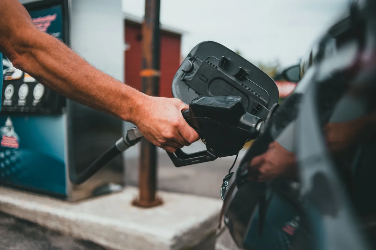 Close-up of a hand holding a nozzle while refueling a car at a gas station