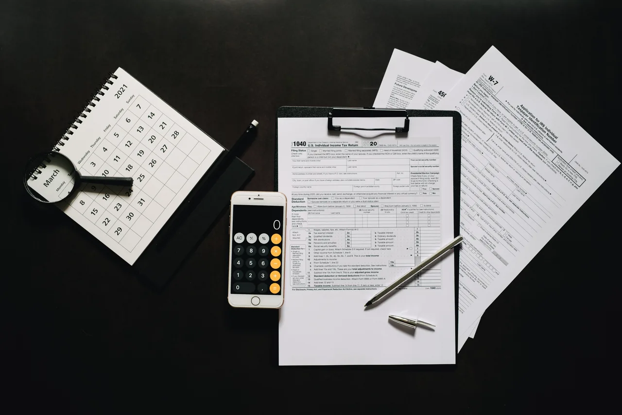Flat lay of financial tools for tax preparation including forms, calculator, and calendar
