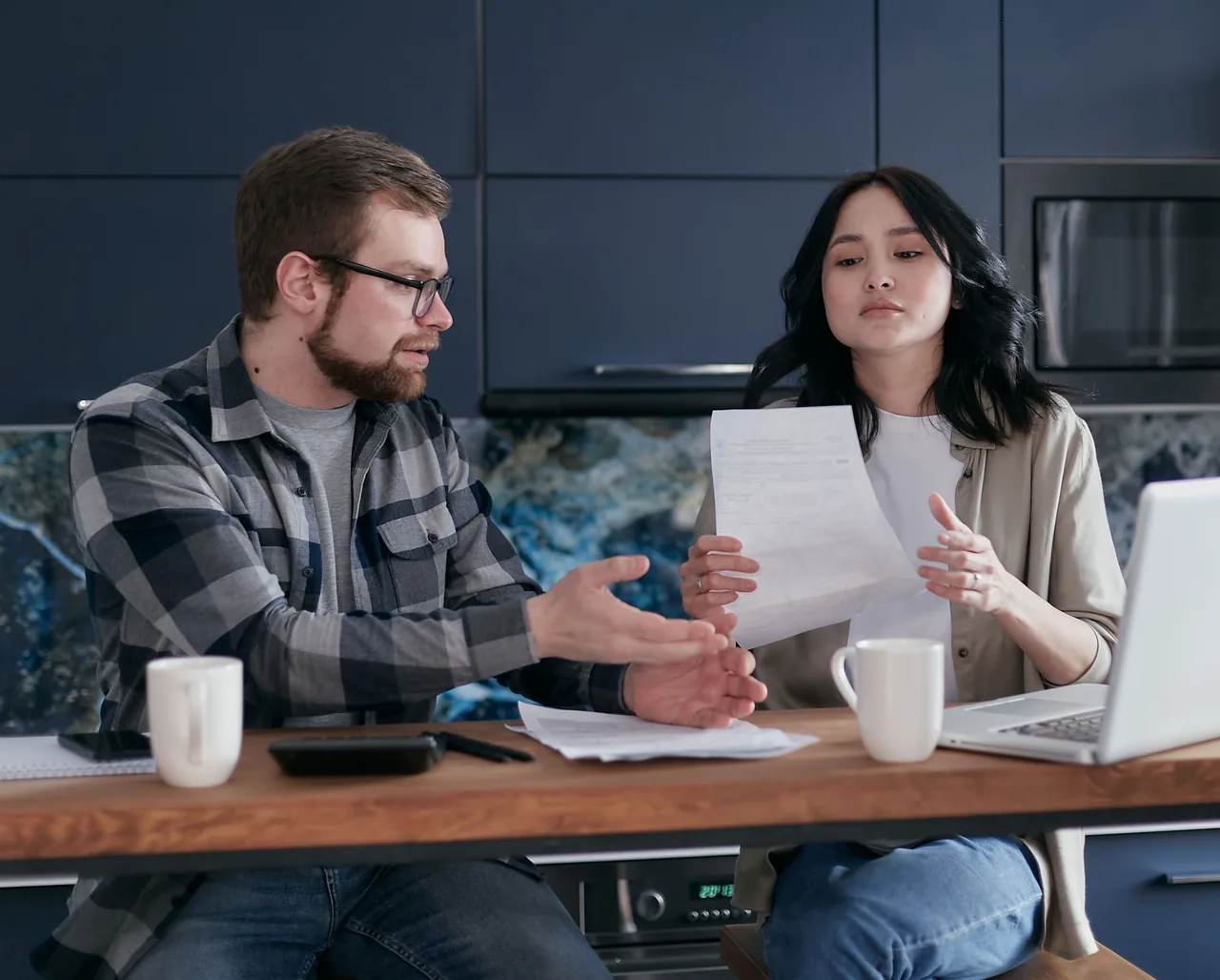A couple having a discussion over financial documents at home with a laptop