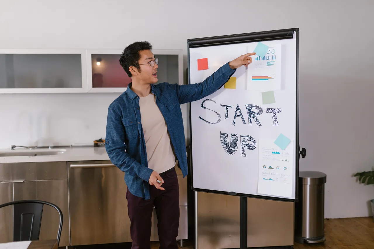 Man presenting a startup plan on a whiteboard in a modern office setting
