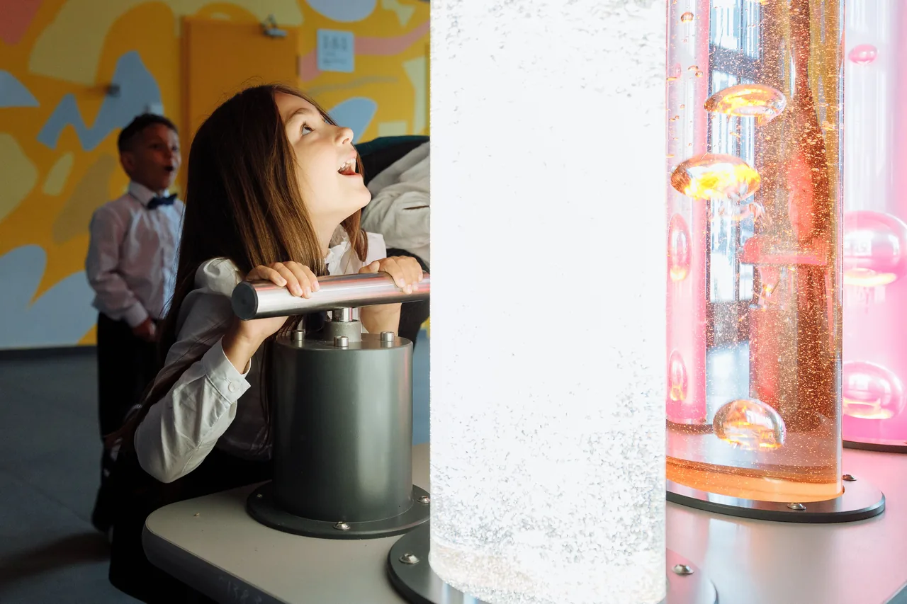 Children engage with interactive science exhibit featuring colorful liquids and lights